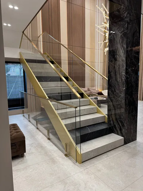 Glasgeländer an der Treppe mit goldfarbenem Titannitrid-Handlauf in einem Einfamilienhaus