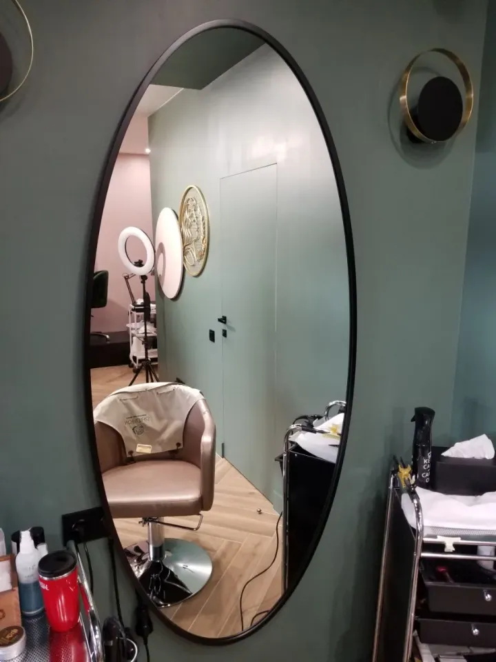 Oval mirror with a dark outline next to a styling chair at the Nofilters salon